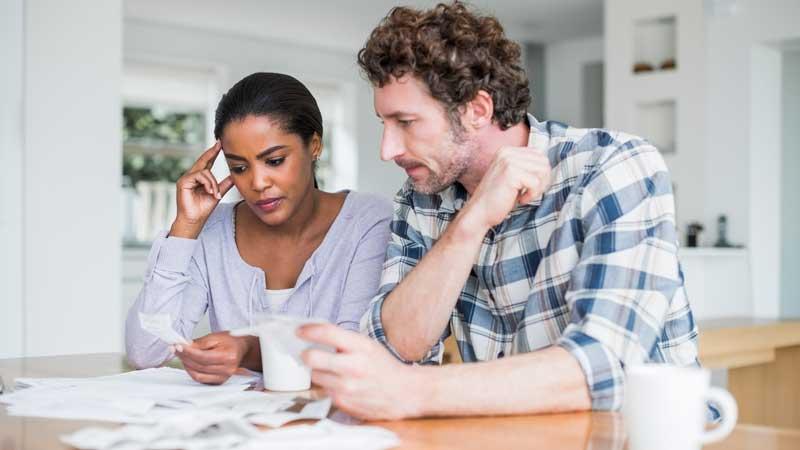 Couple sitting at kitchen table looking at their bills